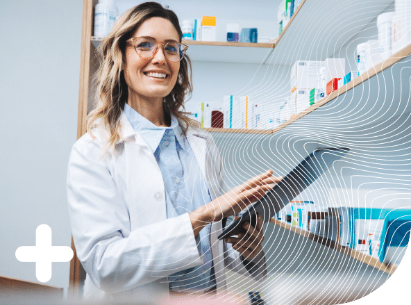 A pharmacist smiling while holding a tablet in a pharmacy.